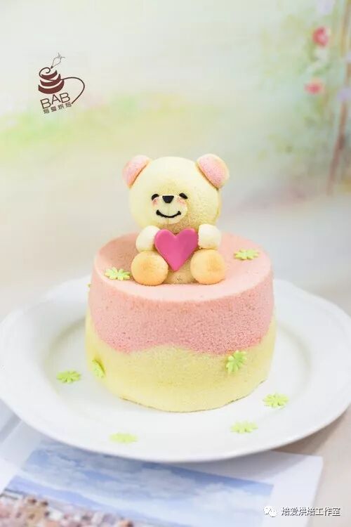 Pink and yellow teddy bear cake holding a heart topper