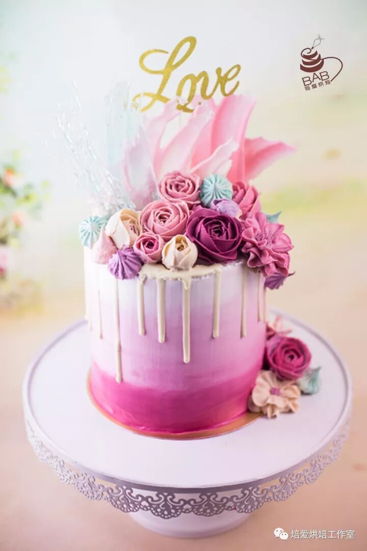 Pink ombre drip cake topped with buttercream roses and a gold Love topper